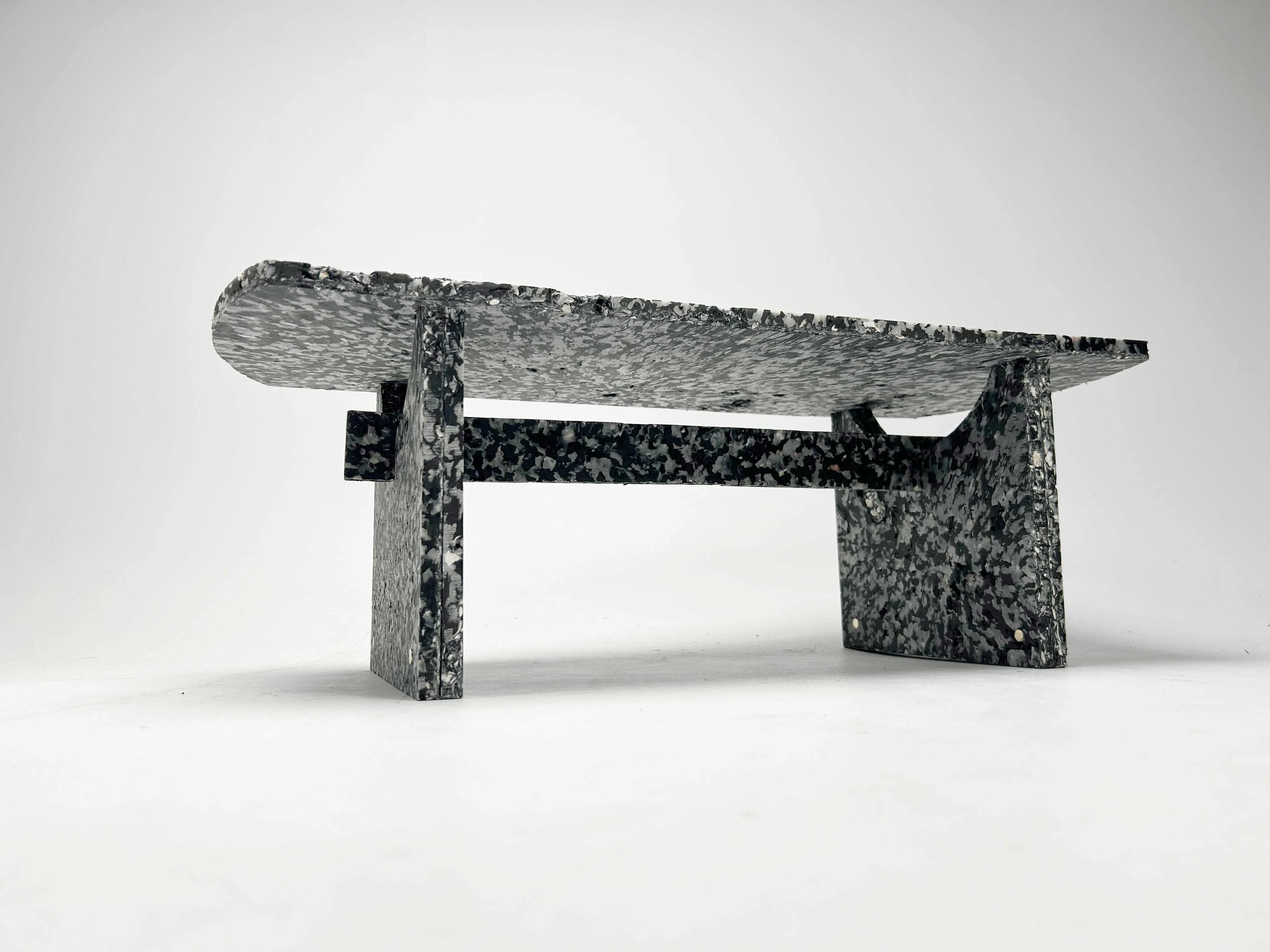 The finished Shio bench in three-quarter view, its speckled composite surface catching the light.